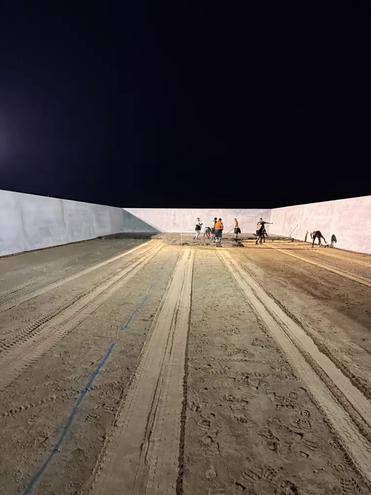 Prepared base of a silage bunker between its precast walls, the crew working at the far end