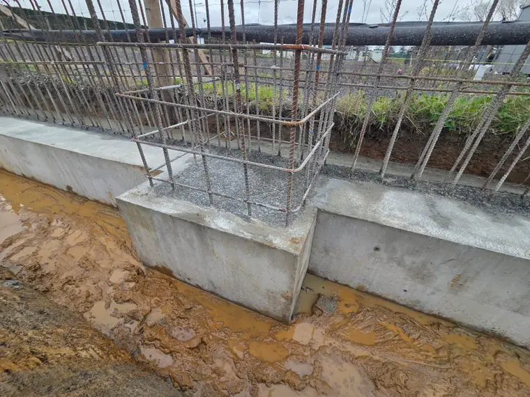 Poured concrete foundation wall with starter bars standing ready for the next lift