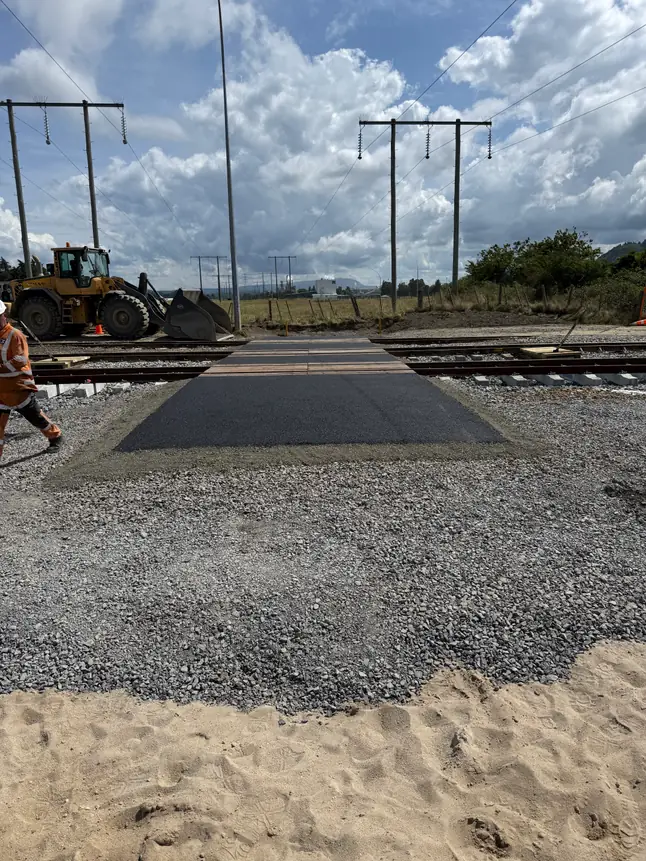 Loader placing hardfill over a geotextile mat on a sandy site beneath the power lines