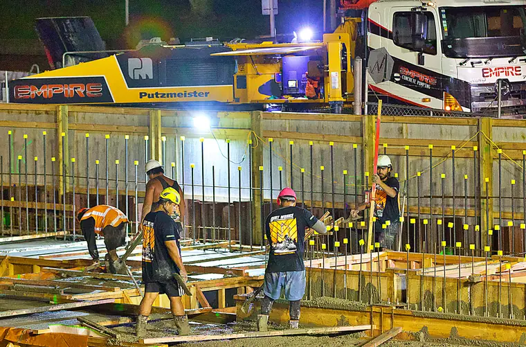 Night concrete pour on a commercial job, the crew working the deck with a boom pump overhead