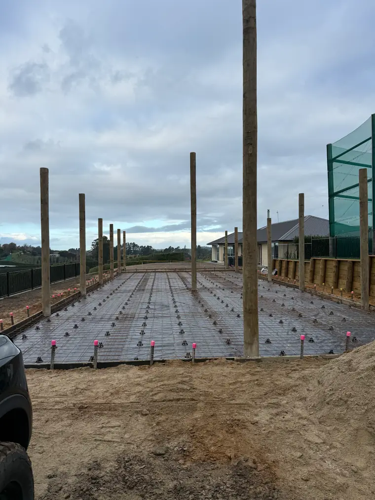 Reinforcing mesh laid out around new posts for a covered area beside a house